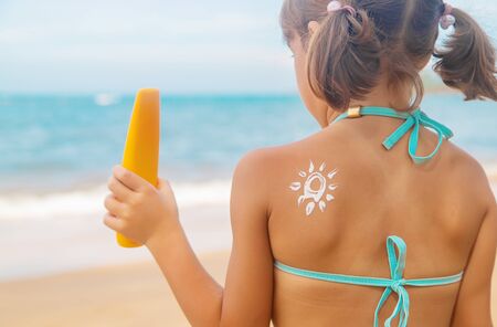 Child on the beach with sunscreen on his back. Selective focus. Travel.