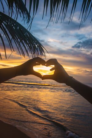 A girl and a man make hands a heart at sunset. Sri Lanka. Selective focus. nature.