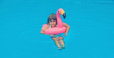 A child swims in a pool with a circle of flamingos. Selective focus.