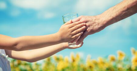 The father gives the child water in the background of the field. Selective focus. natureの写真素材