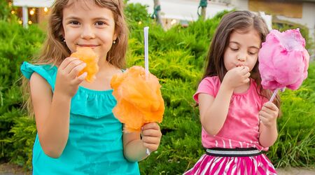Children eat cotton candy in the park. Selective focus.