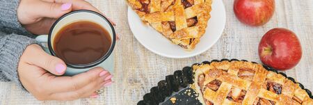 Girl with a cup of tea and a pie with apples and cinnamon. Selective focus. food.の写真素材