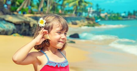 A child with a starfish and shells in his hands on the beach. Selective focus.の写真素材