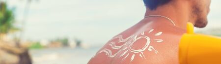 A man on the beach with sunscreen on his back. Selective focus.