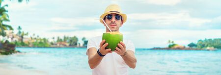 A man on the beach drinks coconut. Selective focus.の写真素材