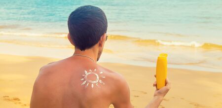 A man on the beach with sunscreen on his back. Selective focus. Travel.の写真素材