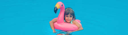 A child swims in a pool with a circle of flamingos. Selective focus.の写真素材
