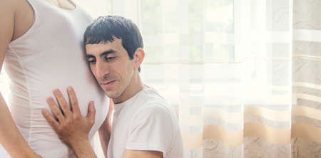 A pregnant woman and a father of a child hug a belly. Selective focus. NATURE.の写真素材