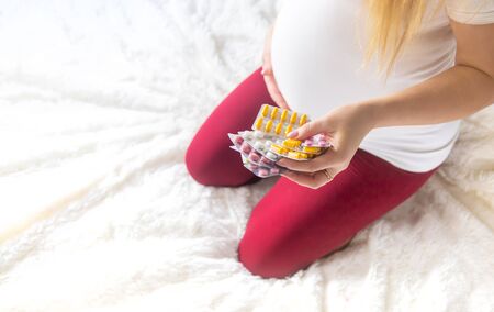 A pregnant woman holds many pills in her hands. Selective Focus. people.の写真素材