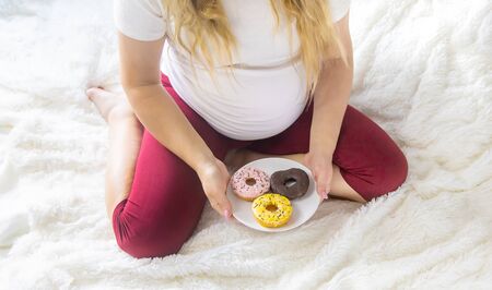 A pregnant woman eats sweet donuts. Selective Focus. Food.の写真素材