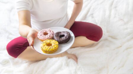 A pregnant woman eats sweet donuts. Selective Focus. Food.の写真素材