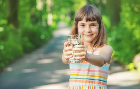 A child drinks water from a glass on the nature. Selective focus. Drink.の写真素材