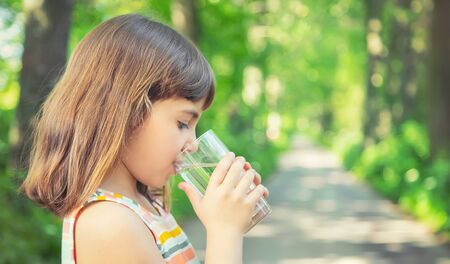 A child drinks water from a glass on the nature. Selective focus. Drink.の写真素材