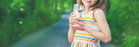 A child drinks water from a glass on the nature. Selective focus. Drink.の写真素材