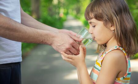 The father gives the child a glass of fresh water. Selective focus. nature.の写真素材