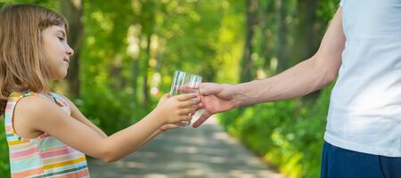 The father gives the child a glass of fresh water. Selective focus. nature.の写真素材