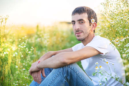 man with flowers in a camomile field. Selective focus.の写真素材