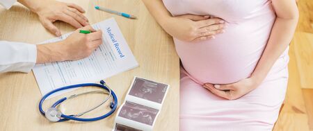 A doctor in a clinic examines a pregnant woman. Selective focus. People.