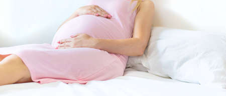 A pregnant woman in bed hugs her stomach. Selective focus. people.の写真素材