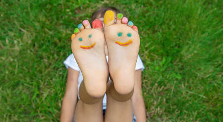 Children's feet with a pattern of paints smile on the green grass. Selective focus. nature.の写真素材