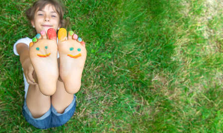 Children's feet with a pattern of paints smile on the green grass. Selective focus. nature.の写真素材