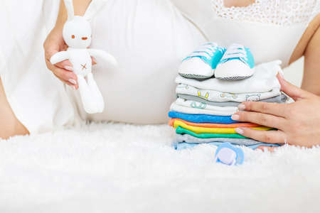 Baby clothes and a pregnant woman. Selective focus. people.の写真素材