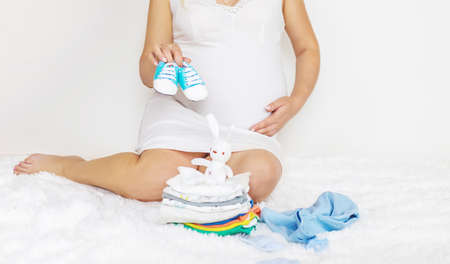 Baby clothes and a pregnant woman. Selective focus. people.