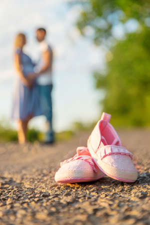 Pregnant woman and man baby shoes. Selective focus. nature.の写真素材