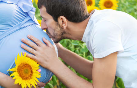 Pregnant woman and man in a field of sunflowers. Selective focus. nature.の写真素材