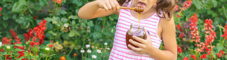 Child eats honey summer photo. Selective focus. nature.の写真素材
