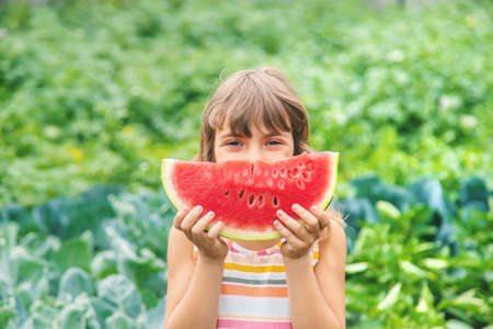 A child on a picnic eats a watermelon. Selective focus.の写真素材