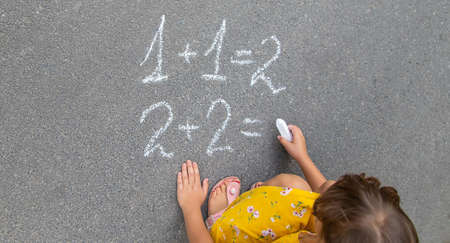 The child writes math on the pavement. Selective focus. summer.の写真素材