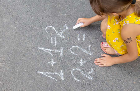 The child writes math on the pavement. Selective focus. summer.の写真素材