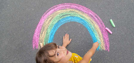 A child draws a rainbow on the asphalt. Selective focus. kid.の写真素材