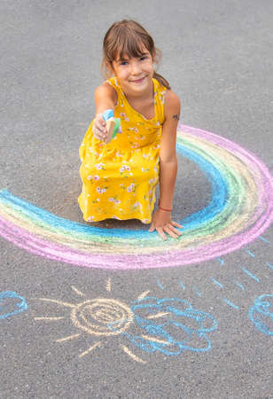A child draws a rainbow on the asphalt. Selective focus. kid.の写真素材