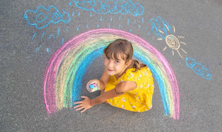 A child draws a rainbow on the asphalt. Selective focus. kid.の写真素材
