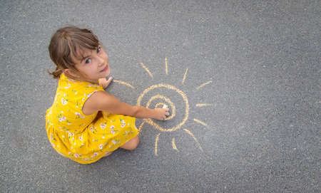 The child draws the sun on the asphalt. Selective focus. nature.