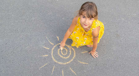 The child draws the sun on the asphalt. Selective focus. nature.の写真素材