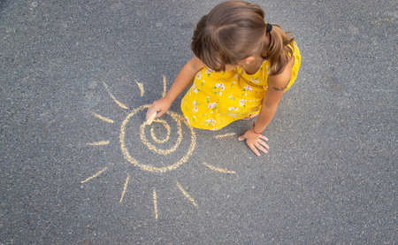 The child draws the sun on the asphalt. Selective focus. nature.の写真素材