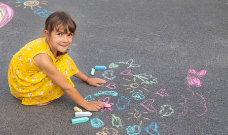 The child draws on the asphalt with chalk. Selective focus. Kid.の写真素材