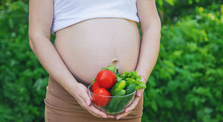 A pregnant woman with vegetables in her hands. Selective focus. food.の写真素材