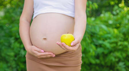 Pregnant woman with an apple in her hands. Selective focus. food.の写真素材