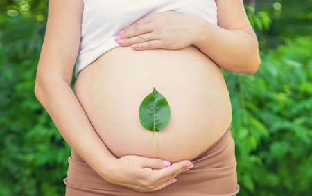 Pregnant belly with a leaf. Selective focus. people.