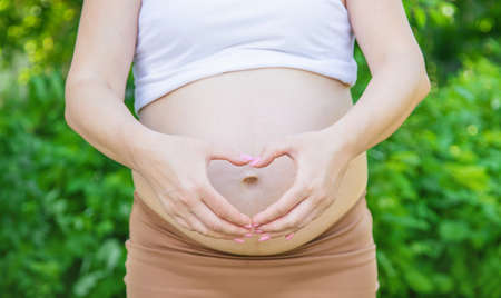 Pregnant woman holds belly heart. Selective focus. nature.の写真素材