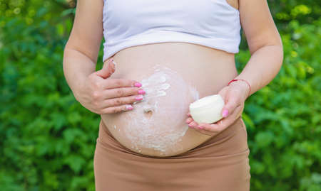 Pregnant woman with cream for stretch marks. Selective focus. nature.の写真素材
