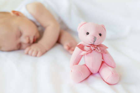 Baby sleeps with a teddy bear on a white background. Selective focus. People.の写真素材