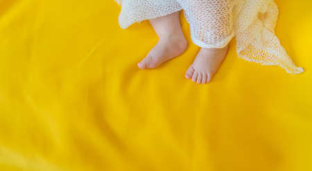 Baby feet on a yellow background. Selective focus. People.
