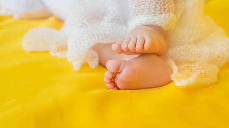 Baby feet on a yellow background. Selective focus. People.