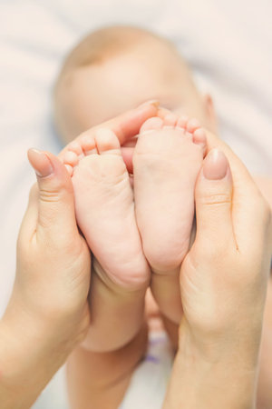 The mother keeps the baby's leg at home. Selective focus. People.の写真素材