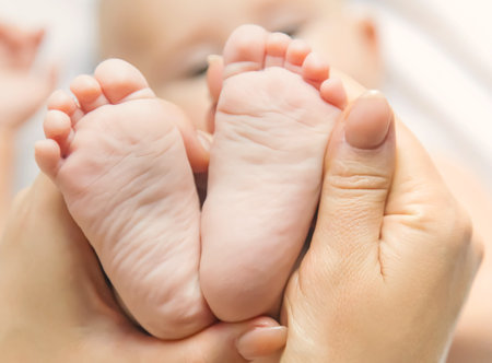 The mother keeps the baby's leg at home. Selective focus. People.の写真素材